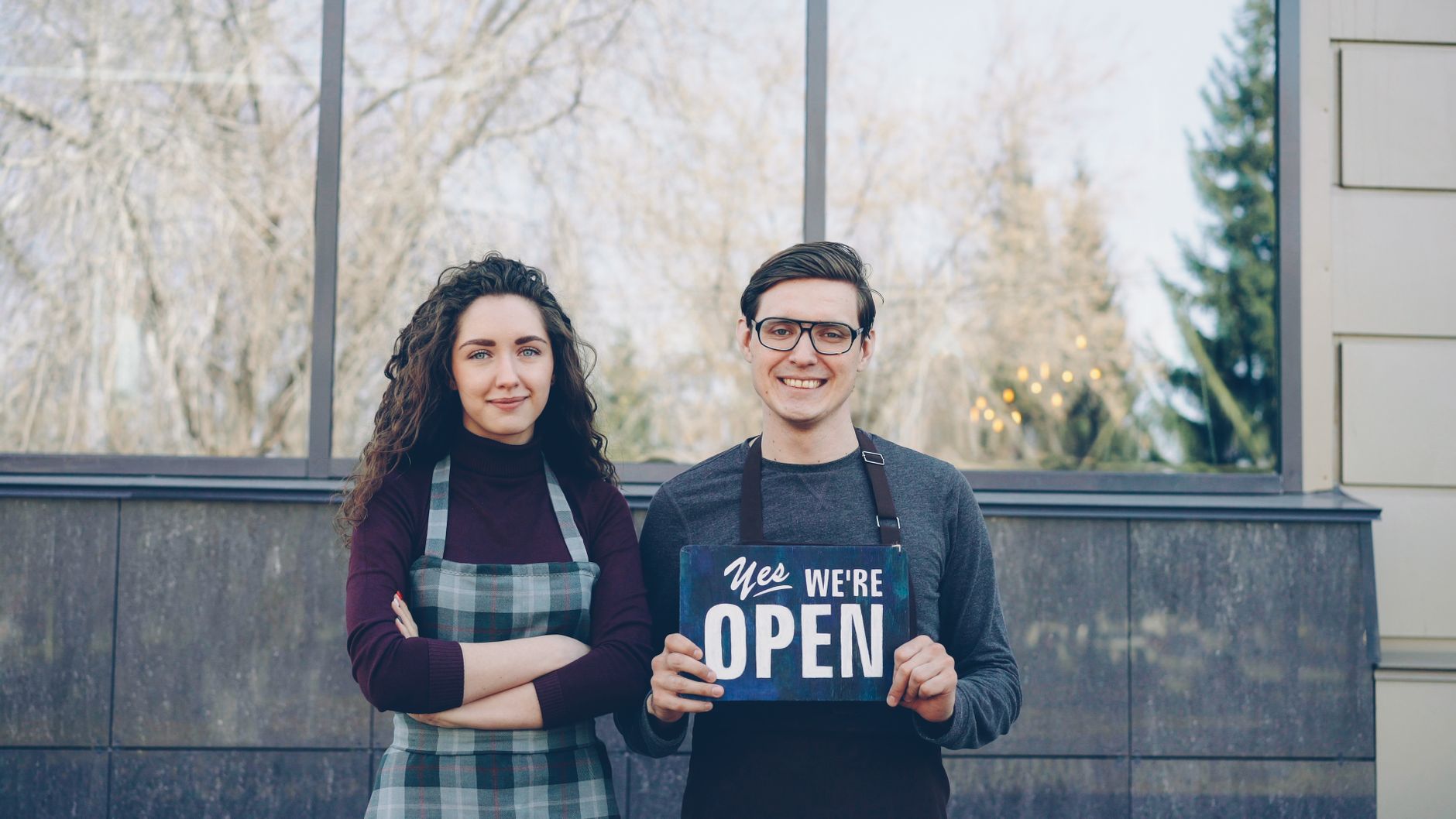 Confident small business owner standing in front of her storefront