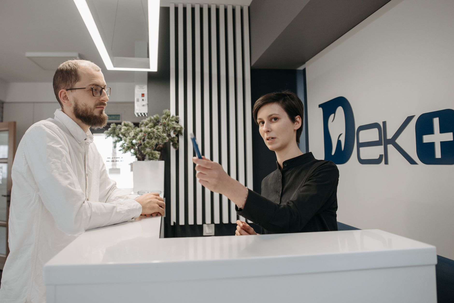 Receptionist checking out a patient at a busy dental clinic front desk