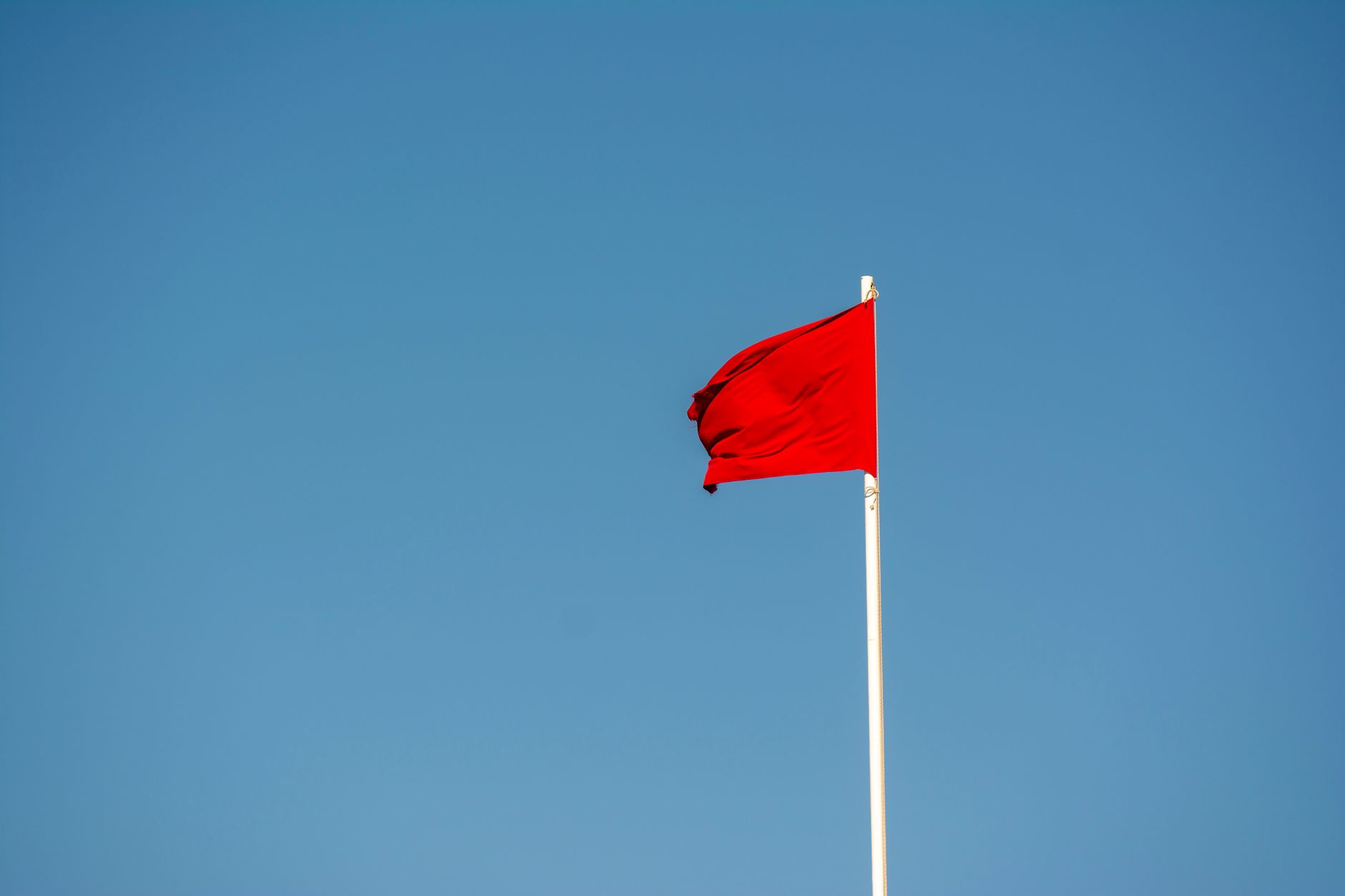 Red flag waving against a blue sky