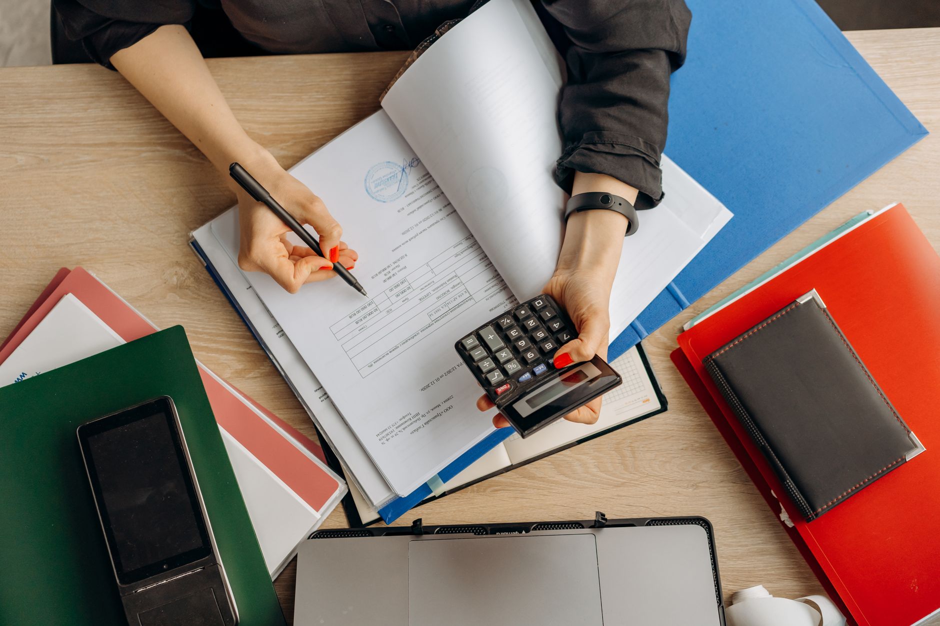 Accountant using a calculator to review financial documents and determine funding costs