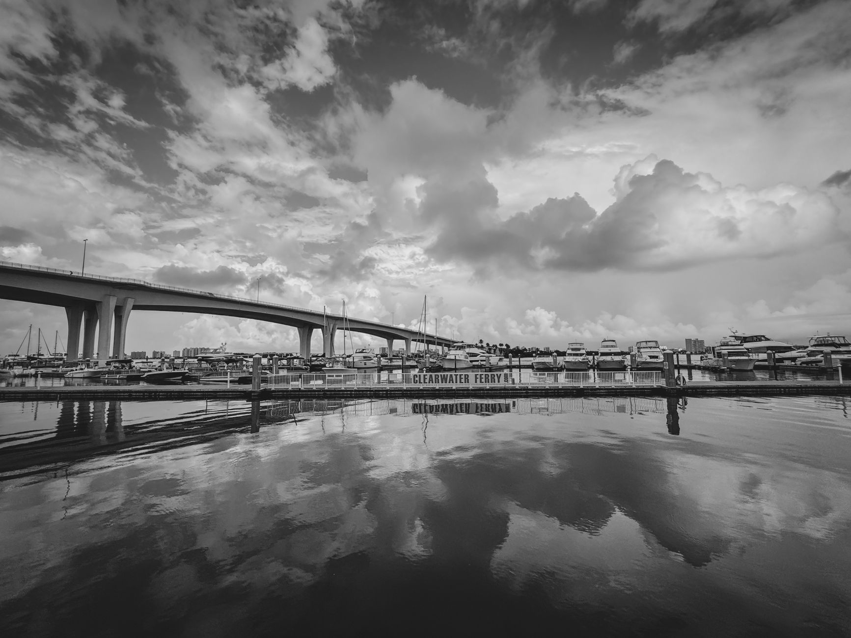 Monochromatic view of Clearwater harbor with bridge and boat reflections.